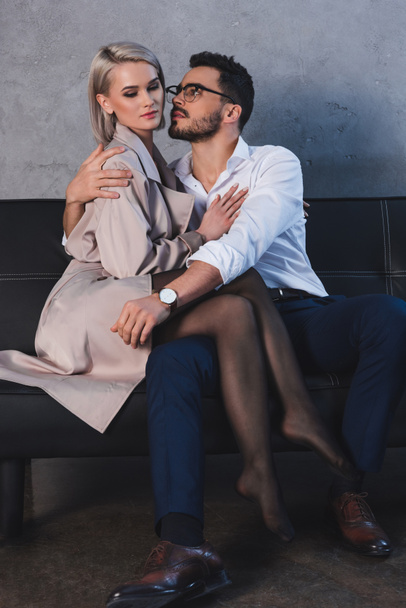 beautiful seductive young couple hugging on sofa in office - Foto, Imagen