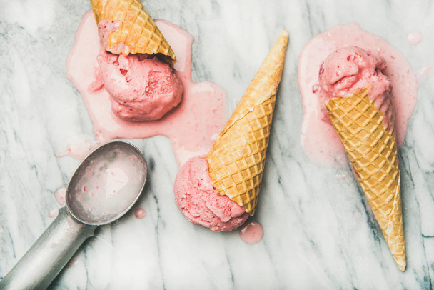 Healthy low calorie summer dessert. Homemade yogurt strawberry ice cream in waffle cones over grey marble background - Photo, Image