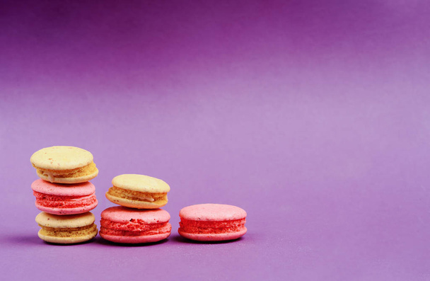 Sweet and colourful french macaroons or macaron on the purple background - Fotó, kép