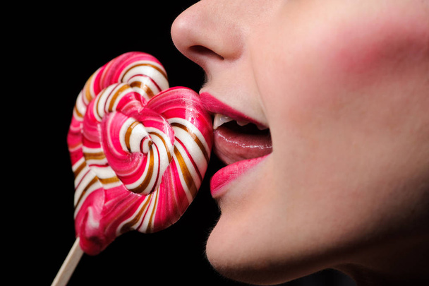 emotional sexy girl with a lollipop over black background in studio - 写真・画像