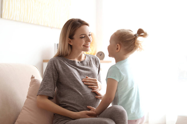 Young pregnant woman with cute daughter at home - Zdjęcie, obraz