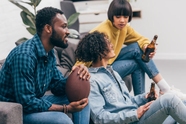 group of multicultural friends with beer bottles watching american football match - 写真・画像
