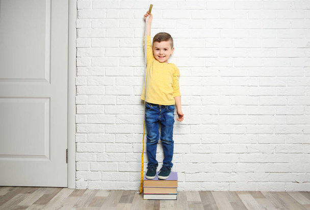 Little boy measuring his height near brick wall - Valokuva, kuva