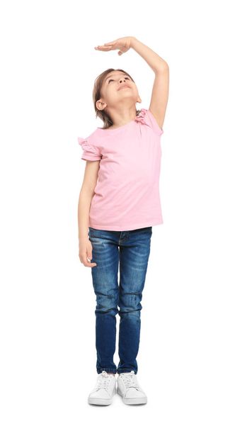 Little girl measuring her height on white background - 写真・画像