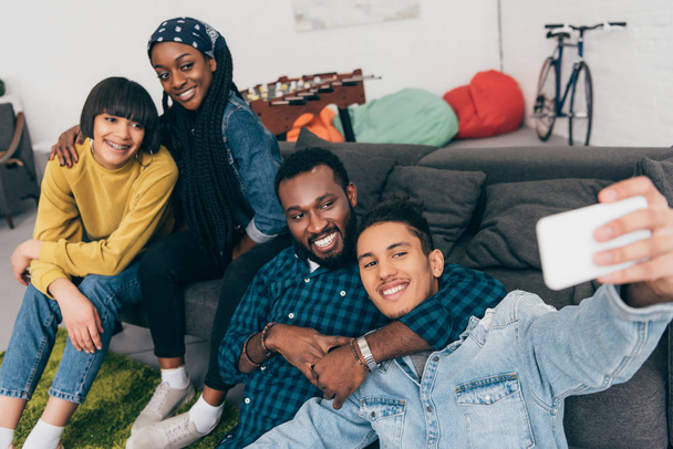  group of young multicultural smiling friends taking selfie on couch - 写真・画像