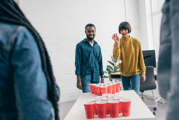 cropped shot of multiethnic group of friends playing beer pong at table  - Photo, Image