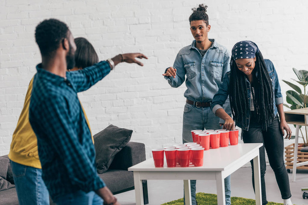 multi-etnische groep van vrienden bier pong spelen aan tafel  - Foto, afbeelding