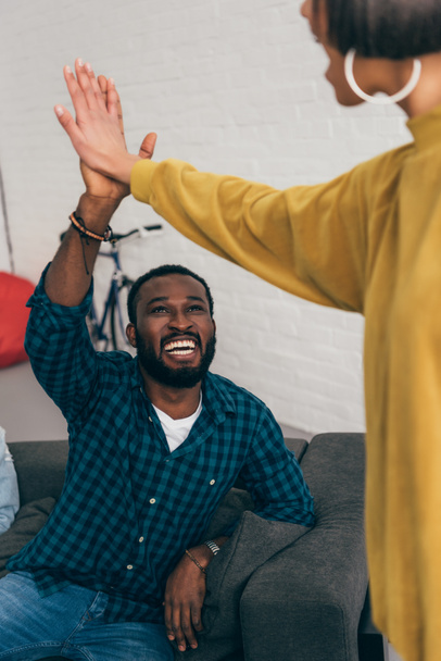 lachende zwarte jongeman nemen hoge vijf aan vriendin  - Foto, afbeelding
