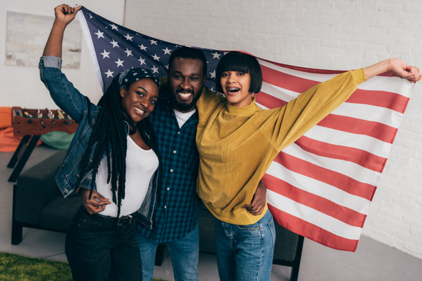 smiling young multiethnic friends standing with flag of USA - Photo, Image
