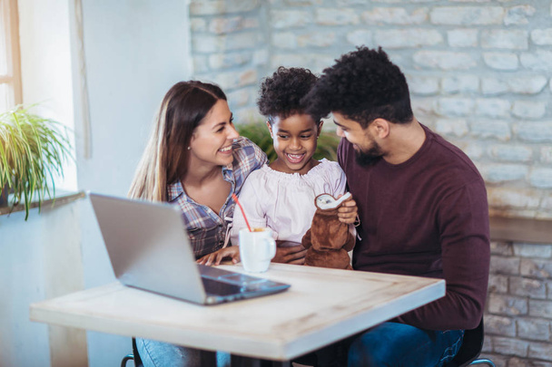 Meisje en gemengd ras ouders laptop thuis gebruiken  - Foto, afbeelding