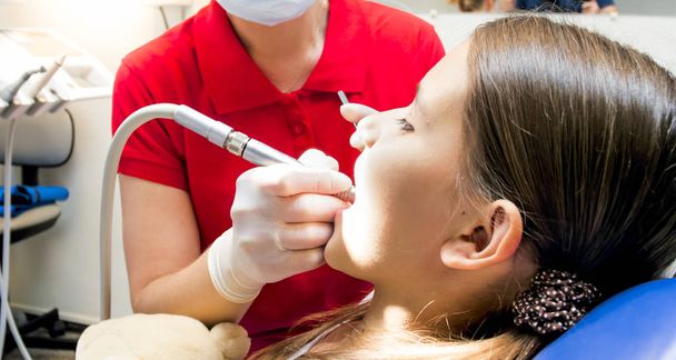 Image rapprochée d'un dentiste pédiatrique utilisant une perceuse dentaire pendant le traitement des dents des fillettes
 - Photo, image