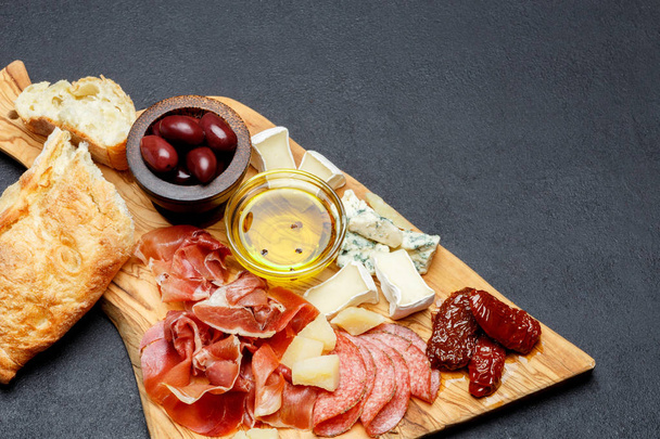Meat and cheese plate with salami sausage, chorizo, parma and brie cheese - Foto, afbeelding