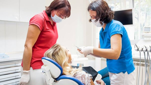 Professionele tandarts vrouwelijke patiënt voor teeth whitening procedure voorbereiding - Foto, afbeelding