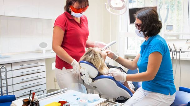 Стоматолог, лечащий зубы пациентов ультрафиолетовой лампой
 - Фото, изображение