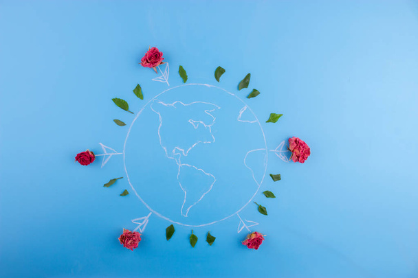 concept with earth and colourful flowers around, planet earth on blue background - Foto, Imagen