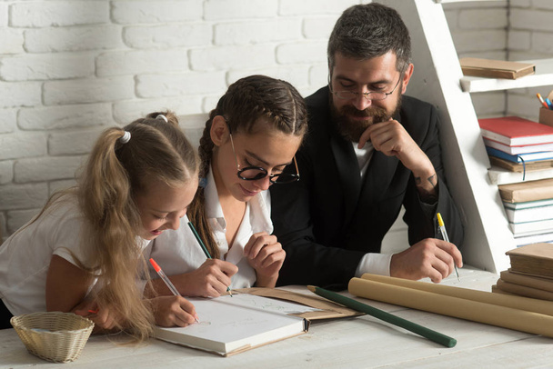 School time of girl sisters with father. school lesson with bearded man tutor and little kid girls - Foto, Imagem
