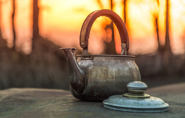 Old kettle on the evening garden, kettle on a metal surface - Photo, Image