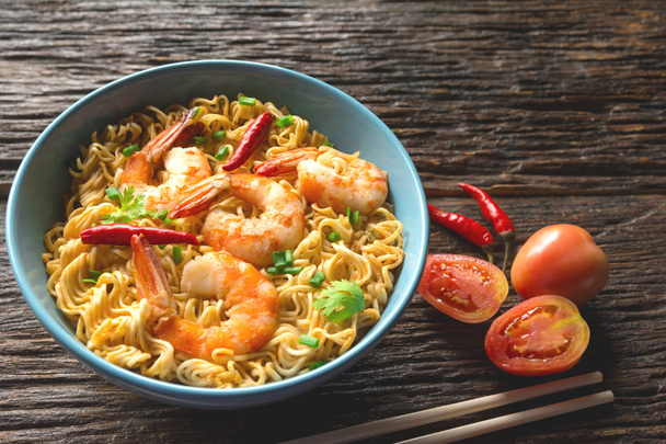 Top view of instant noodles with shrimp and chopsticks on wooden background. - Photo, Image