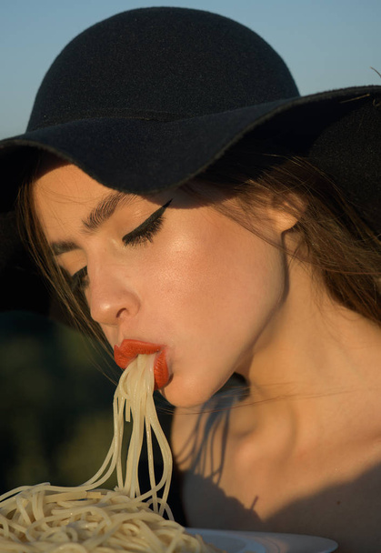 Nice Image of a Beautiful Woman Eating Pasta in Black hat - Фото, зображення
