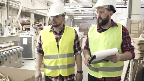 twee arbeiders in de reflecterende vesten en helmen op de meubelfabriek - Video