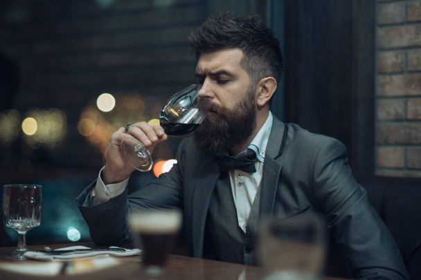 bar customer sit in cafe drinking alcohol. Bearded man rest in restaurant with wine glass. Perfect wine. Date meeting of hipster awaiting in pub. Businessman with long beard drink in cigar club. - Valokuva, kuva
