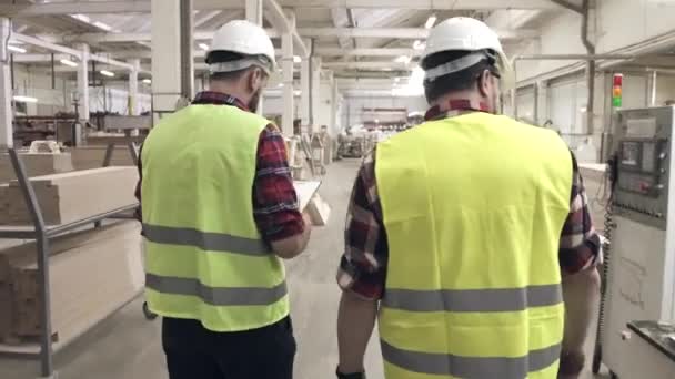 Yeşil yelek ve kask makineleri arasında bir mobilya Fabrikası'nda konuşan iki işçi - Video, Çekim