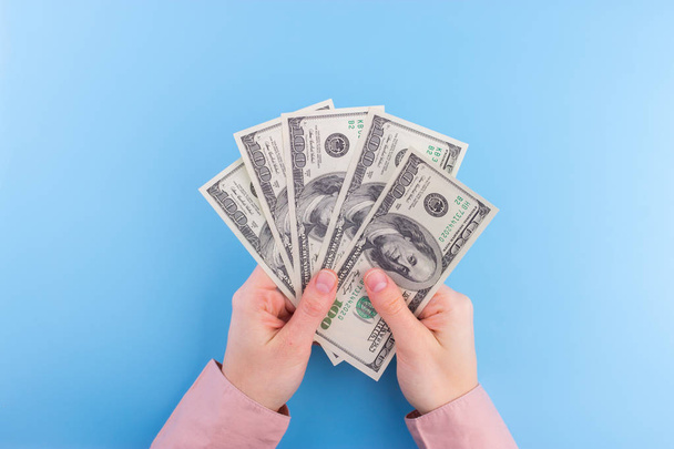 hand hold dollar bills on blue background - Foto, afbeelding
