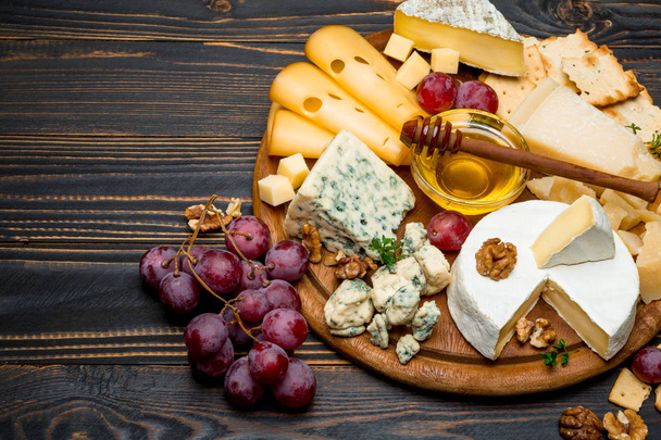 various types of cheese - brie, camembert, roquefort and cheddar on wooden board - Fotografie, Obrázek