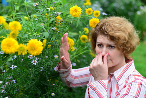 woman with with rhinitis near the yellow flowers - Foto, Imagem
