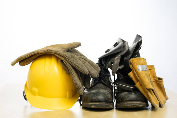 Protective helmet and work boots on a wooden table. Safety and h - Fotó, kép