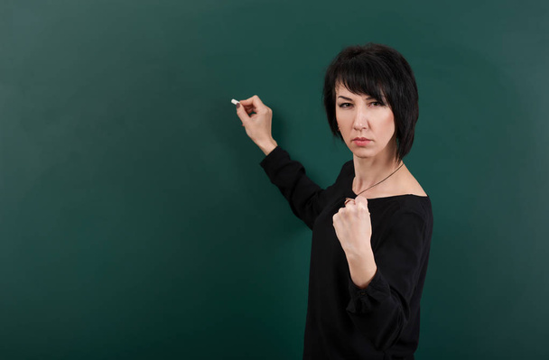 serious girl teacher posing by chalk Board, learning concept, green background, Studio shot - Foto, Imagen