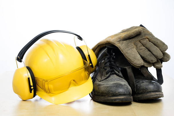 Protective helmet and work boots on a wooden table. Safety and h - Φωτογραφία, εικόνα