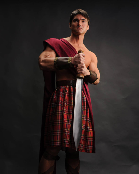 pohledný highlander drží lesklý meč - Fotografie, Obrázek