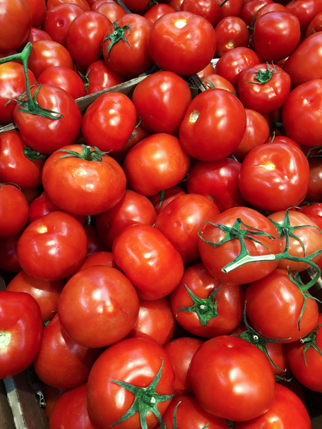 Вкусные спелые красные помидоры на ветке на рынке
  - Фото, изображение
