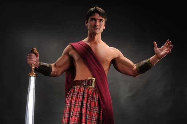 der gutaussehende Highlander hält ein glänzendes Schwert - Foto, Bild