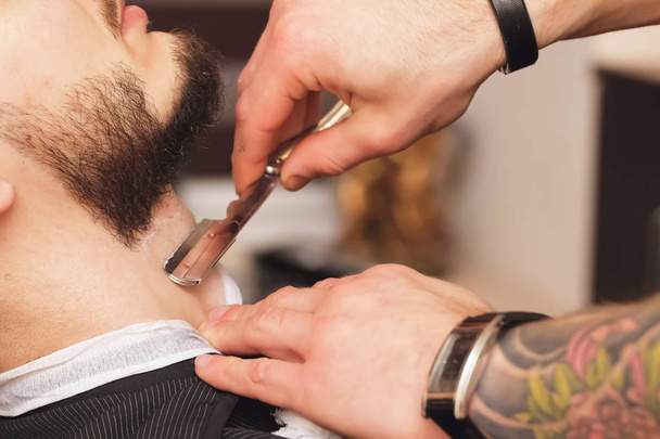 Client during beard shaving in barber shop - Фото, изображение