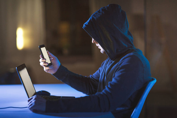 hacker with laptop and smartphone in dark room - Foto, immagini