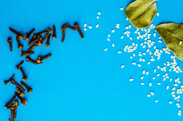 chiodi di garofano, sesamo e foglie di alloro su sfondo blu con un posto sotto il testo
 - Foto, immagini