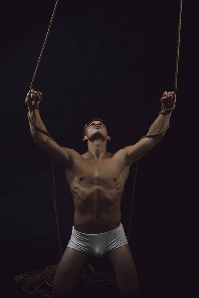 Man with muscular body on rope. Circus gymnast at pilates or yoga training. Sport workout for bodybuilder. Fitness dieting and flexibility in acrobatics. Sexy macho man do gymnastic - Zdjęcie, obraz