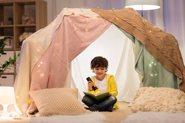 happy little boy reading book in kids tent at home - Foto, afbeelding