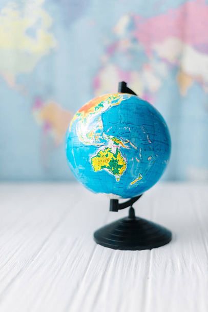 Globo em uma mesa branca de madeira no fundo de um mapa do mundo
. - Foto, Imagem