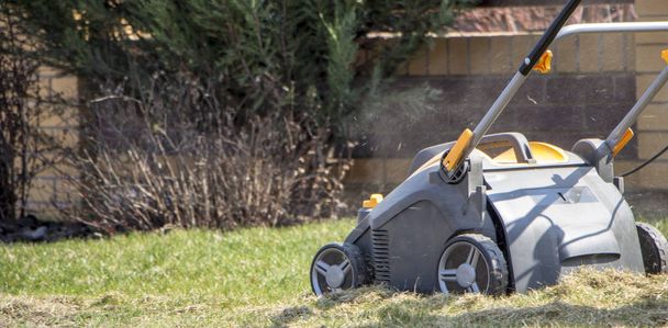 Jardineiro operando máquina de aeração do solo no gramado de grama - Foto, Imagem