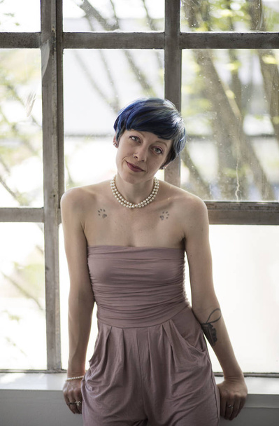 Photo of a very attractive woman with beautiful blue eyes blue hair. She is looking straight at the camera and wearing a beautiful little mauve outfit. - Fotó, kép
