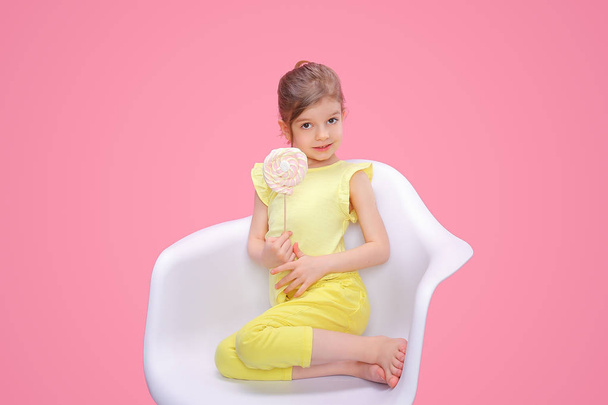 Content girl with candy in chair - Photo, Image