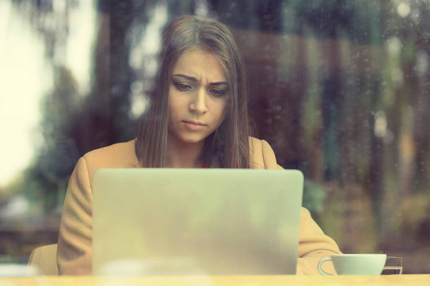 femme bouleversée assis dans le café devant l'écran de tenue d'ordinateur portable dans
 - Photo, image