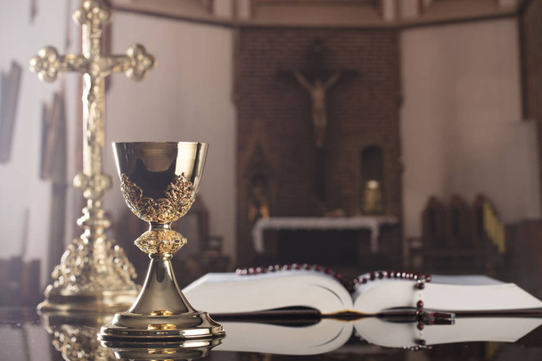 First holy communion theme. The Cross, Holy Bible, rosary and golden chalice on the altar. - Photo, Image