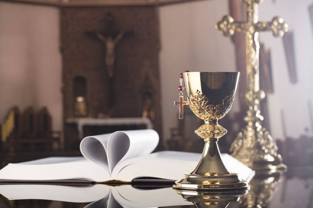 Tema de la primera comunión santa. La Cruz, la Santa Biblia, el rosario y el cáliz de oro en el altar
. - Foto, Imagen