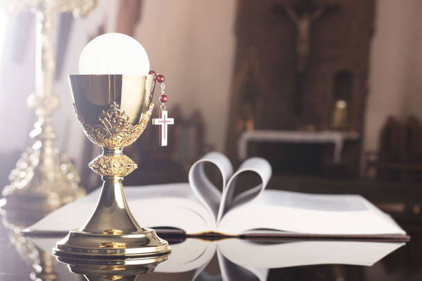 First holy communion theme. The Cross, Holy Bible, rosary and golden chalice on the altar. - Photo, Image