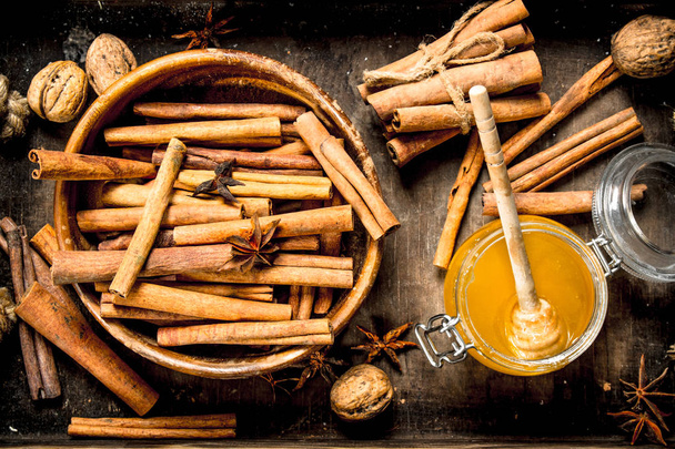 Fresh honey with the cinnamon sticks in a bowl . On rustic background . - Photo, Image