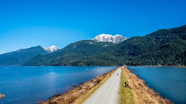 El dique que separa el lago Pitt y el pantano Pitt-Addington rodeado por los picos nevados de la cordillera de la costa en el valle Fraser de Columbia Británica, Canadá
 - Foto, imagen